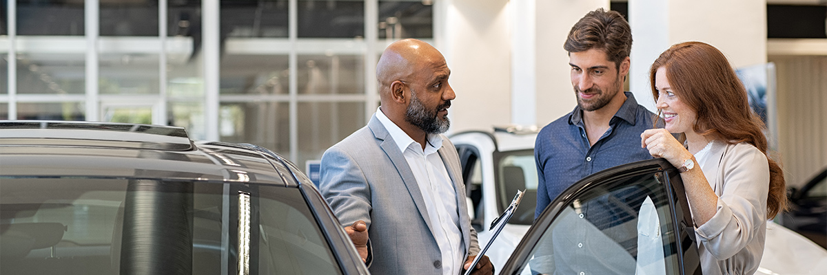 Dealership employee showing customers cars on showroom floor.